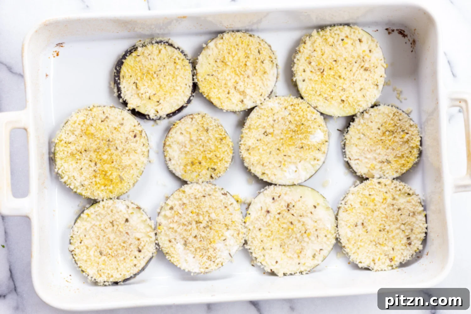 Simple Vegan Eggplant Parmesan 13 Breaded eggplant slices arranged in a baking dish, ready for the oven