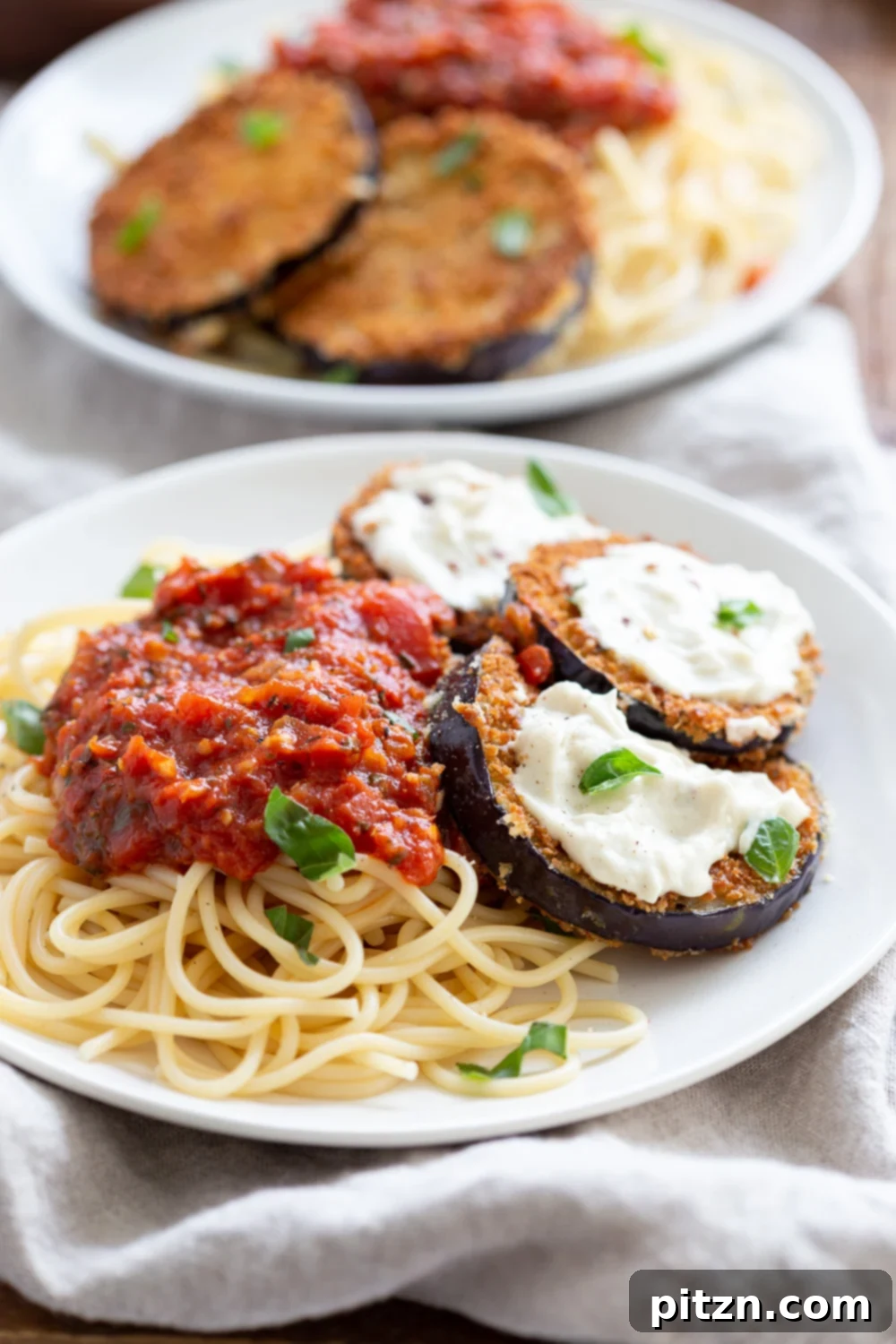 Simple Vegan Eggplant Parmesan 16 Multiple servings of Vegan Eggplant Parmesan with spaghetti on white plates