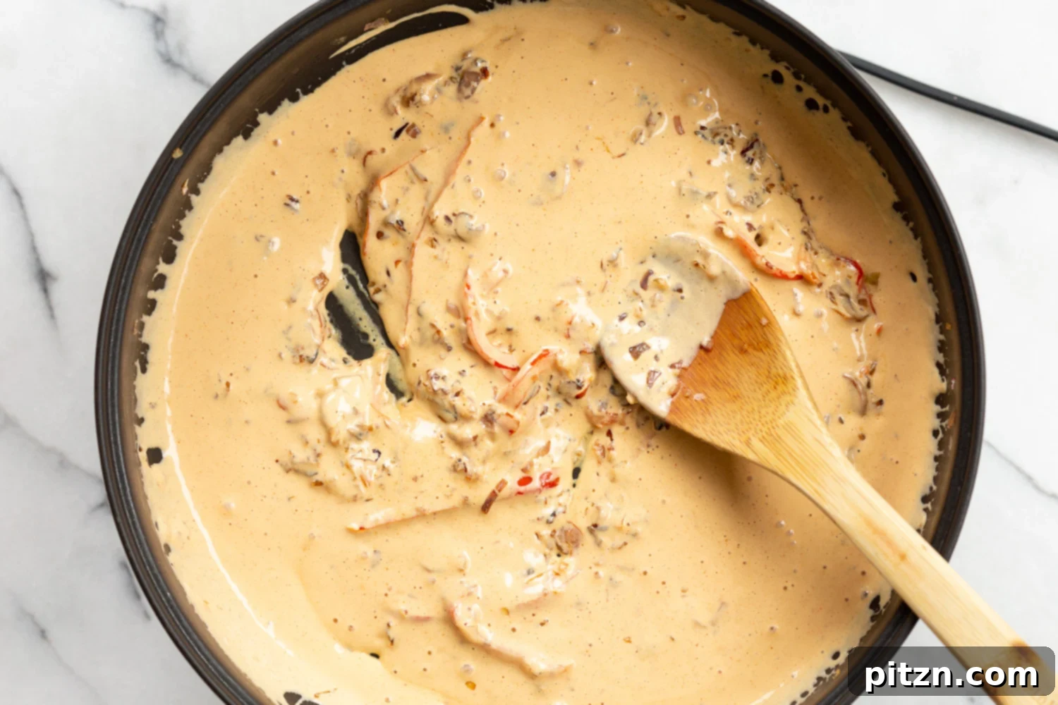 The rich and creamy Cajun pasta sauce simmering in a skillet, with a velvety texture and inviting aroma.