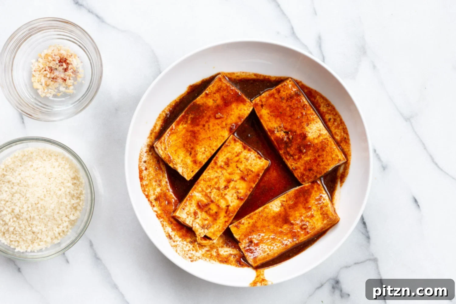 Marinated tofu slices soaking in a flavorful liquid in a white bowl, absorbing all the delicious spices.