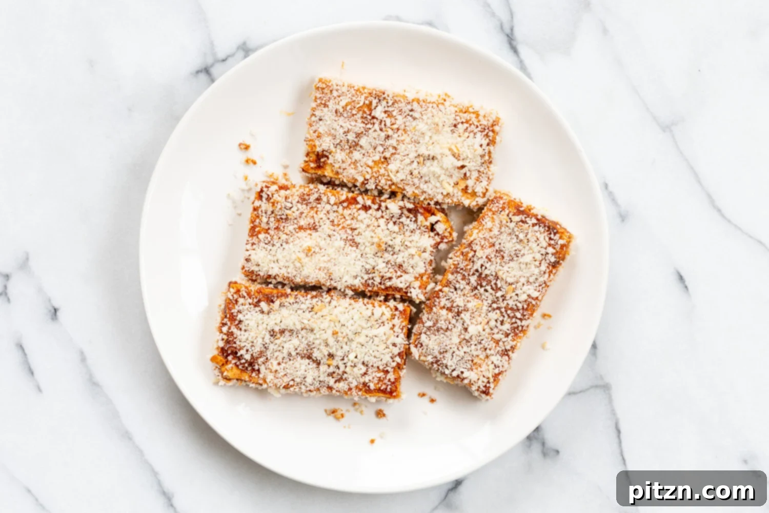 Breaded tofu slices coated in a savory mixture, arranged neatly in a white bowl, ready for cooking.