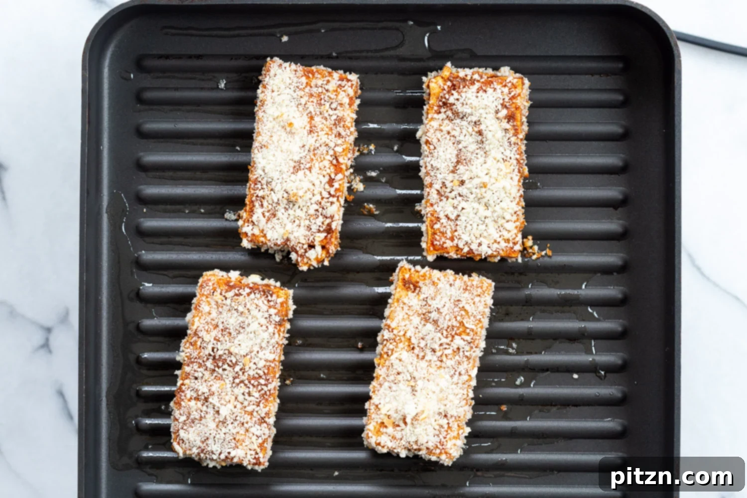 A close-up shot of breaded tofu sizzling in a hot pan, developing a golden-brown and crispy crust.