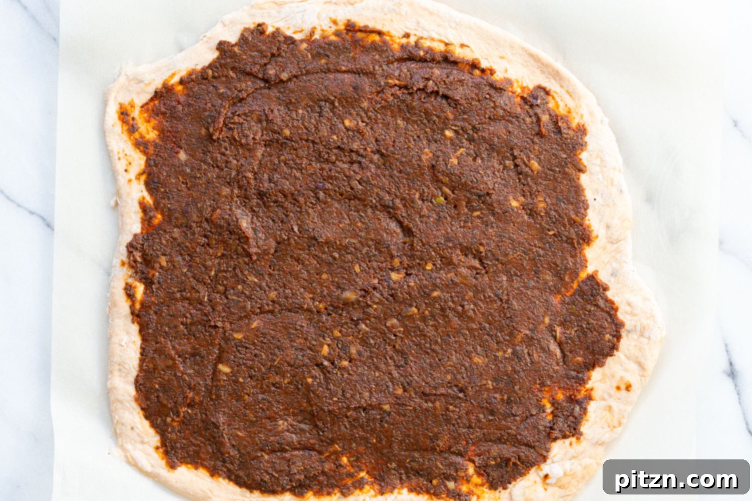 The Ultimate Vegan Pizza Rolls 11 Savory mushroom tomato filling evenly spread over the rolled-out pizza dough for Vegan Pizza Rolls, leaving a border around the edges.