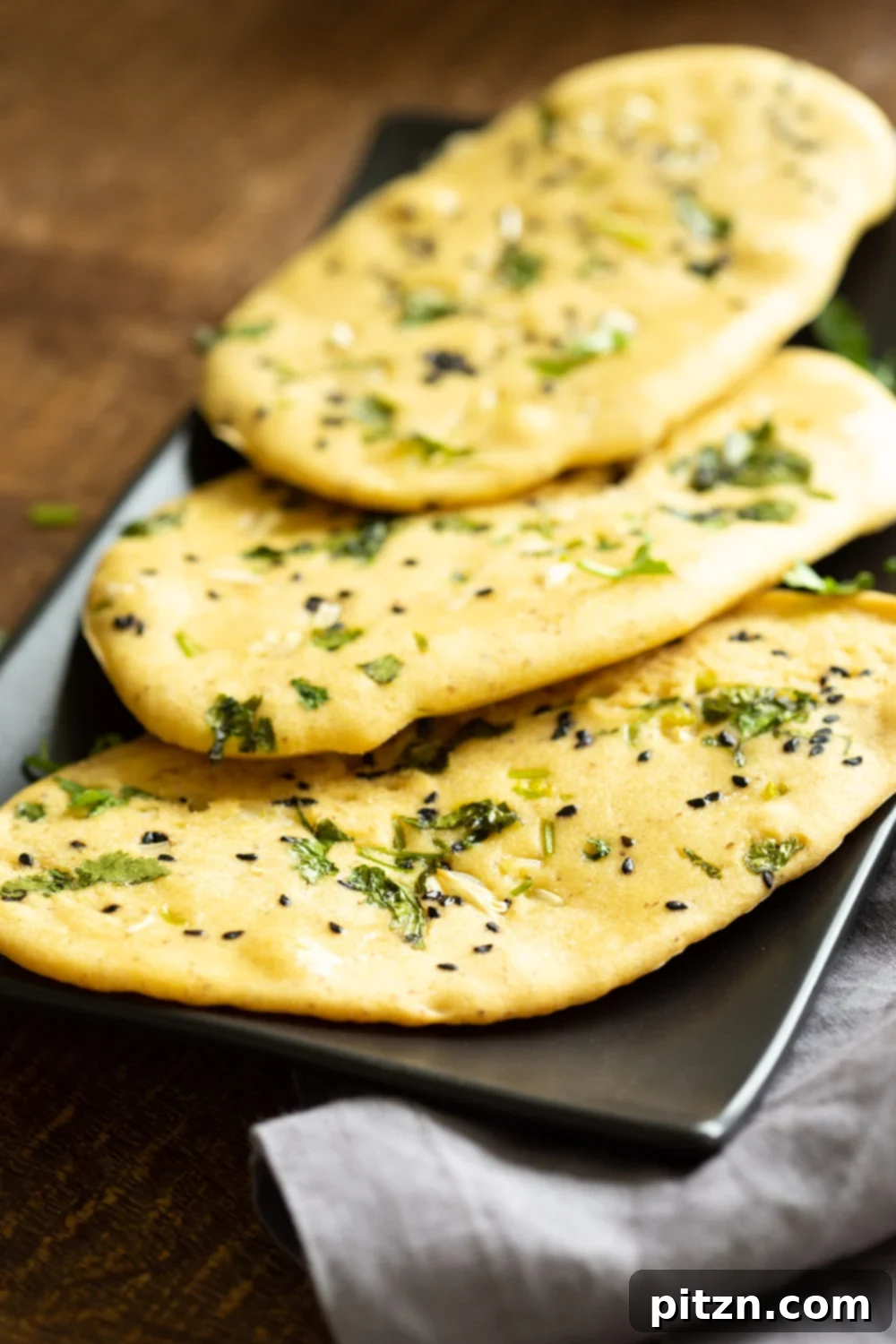 Our Vegan Gluten Free Naan Breads attractively arranged on a black serving board, showcasing their soft, appealing texture