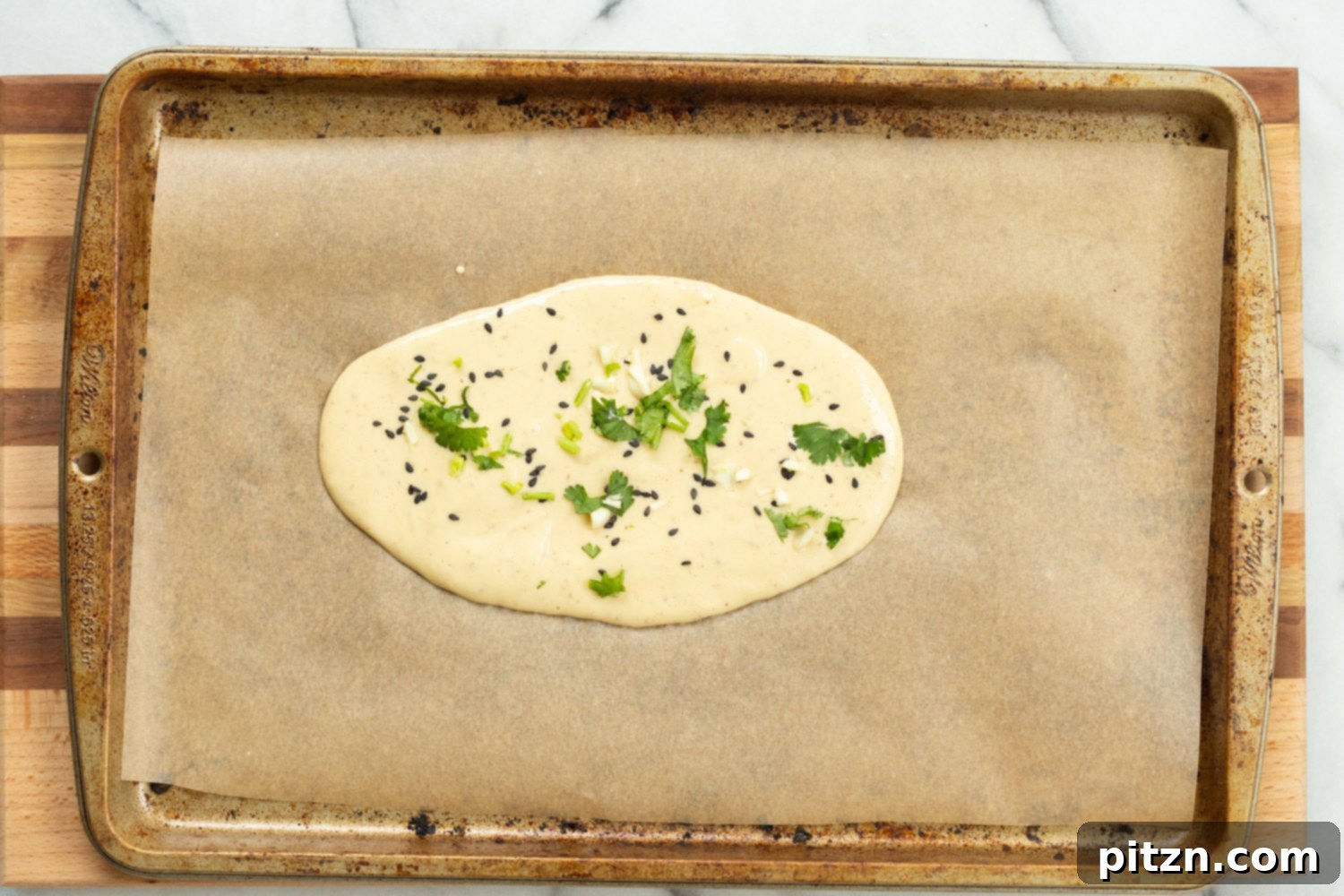 Vegan Gluten Free Naan batter expertly spread on a parchment-lined baking sheet, prepared for baking