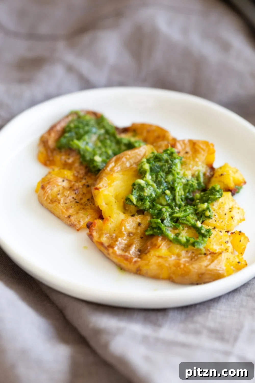 Vegan Smashed Potatoes with Chimichurri Sauce on a white plate, ready to be served.