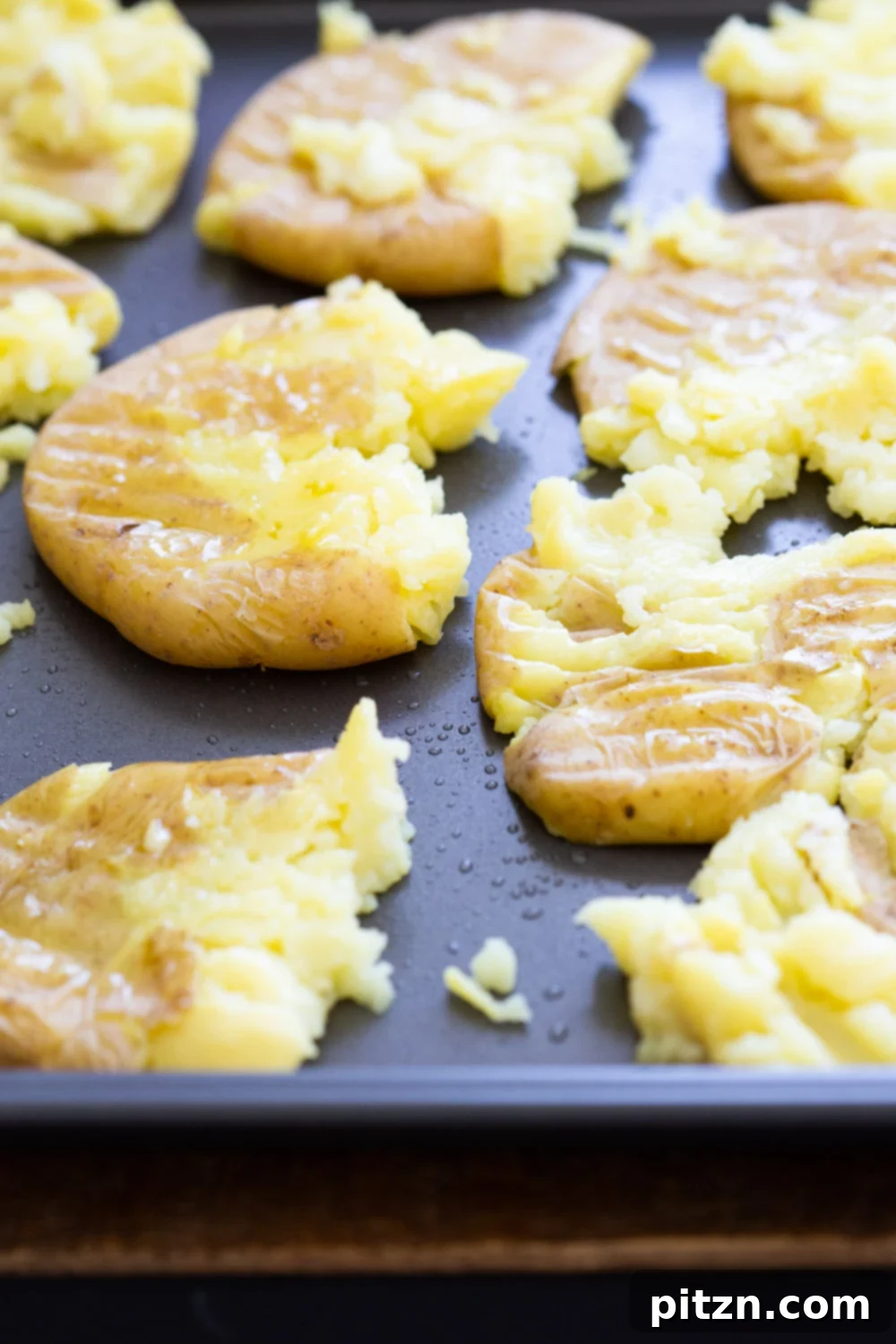 Cooked potatoes pressed on a baking sheet for our Crispy Vegan Smashed Potatoes with Chimichurri.