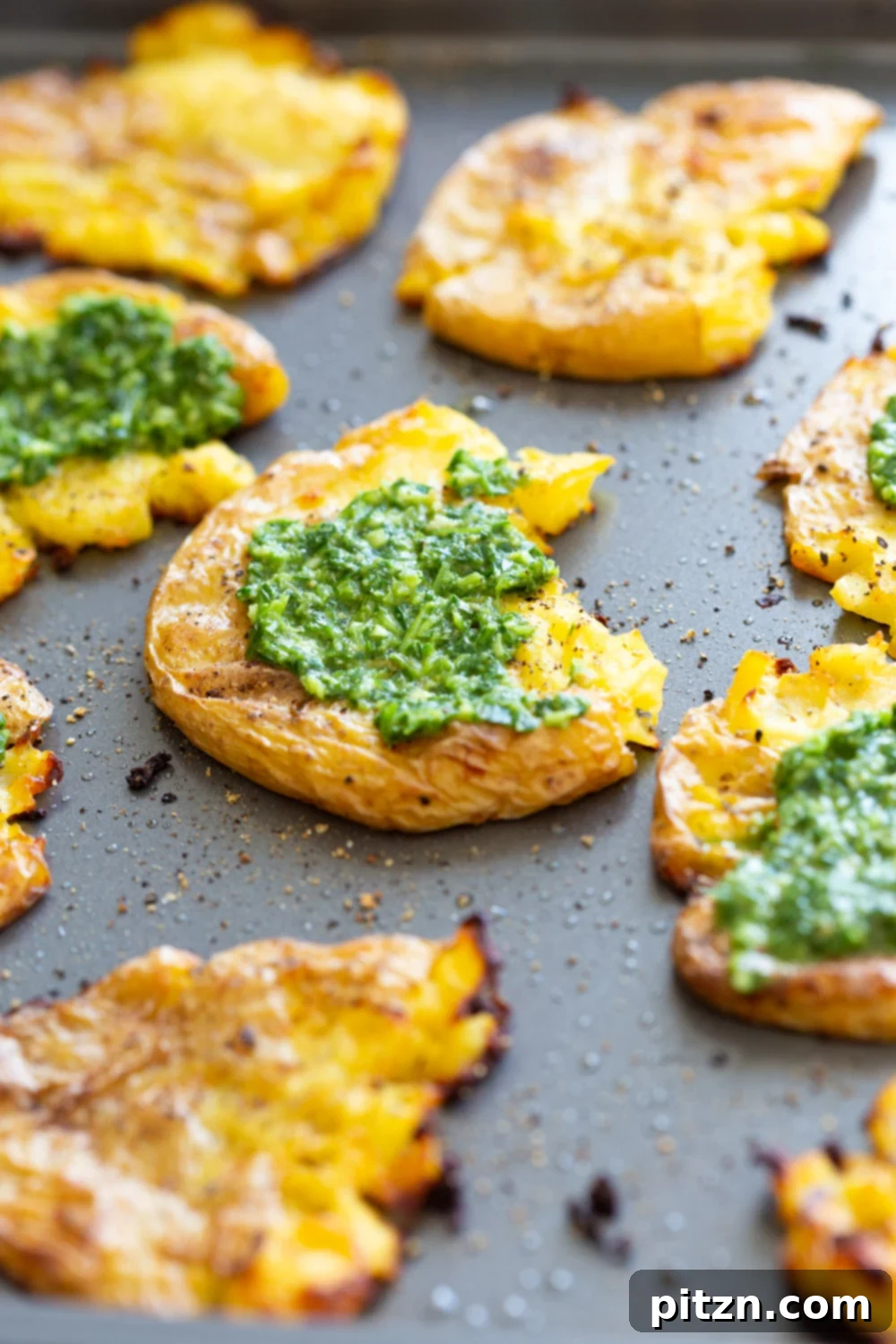 Crispy Vegan Smashed Potatoes with Chimichurri Sauce on a Grey Baking sheet, freshly baked.