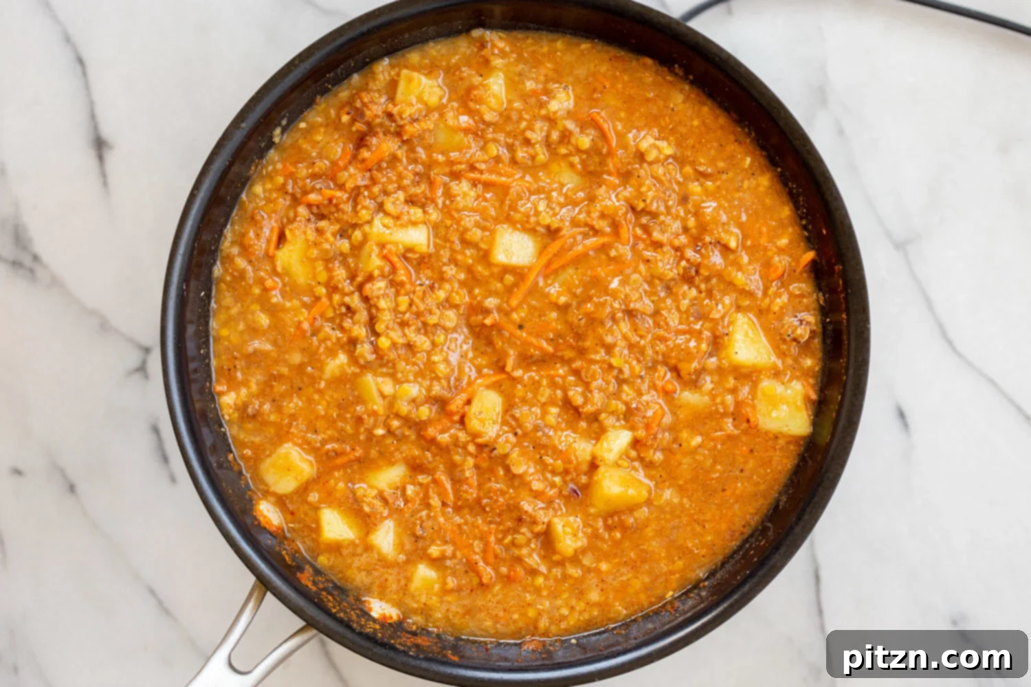 The finished Vegan Keema Madras, a hearty blend of lentils, potatoes, and spices, served in a black skillet.