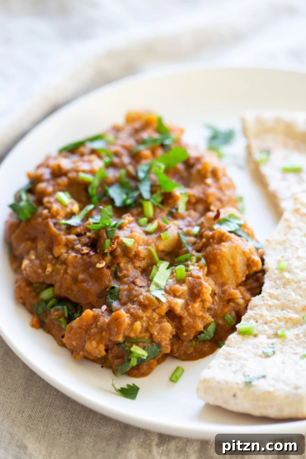 A serving of Vegan Keema Madras on a white plate, garnished with fresh cilantro and lime wedges.