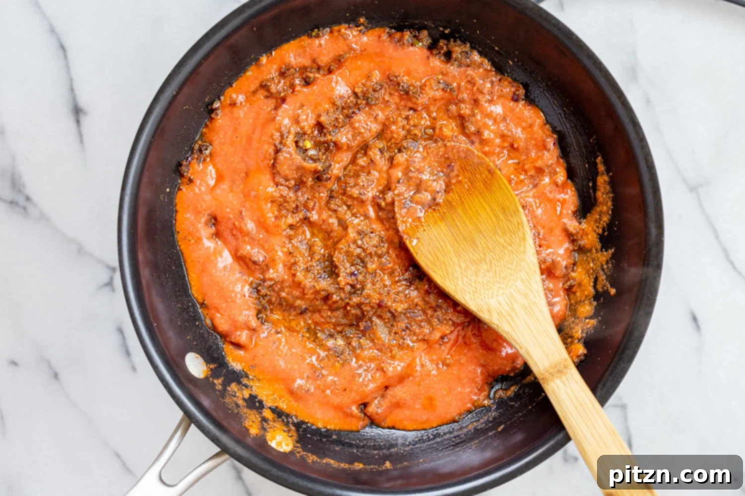 Creamy tomato and coconut puree added to the skillet with spices and aromatics for Vegan Keema Madras.