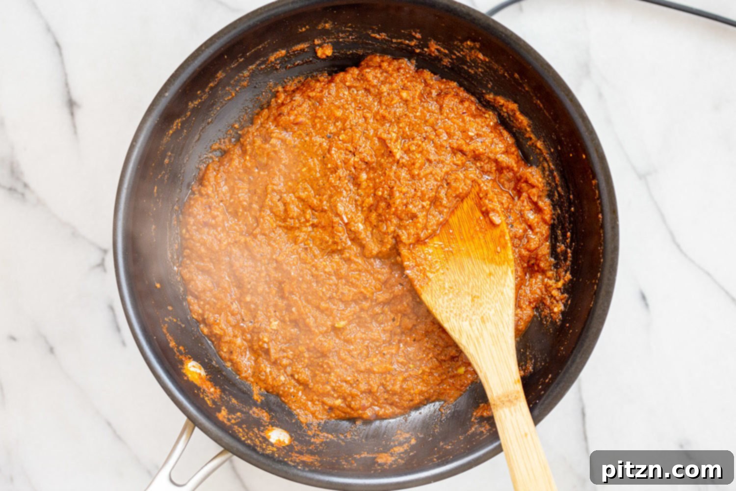 The rich, thickened tomato-coconut sauce for Vegan Keema Madras simmering in a black skillet.
