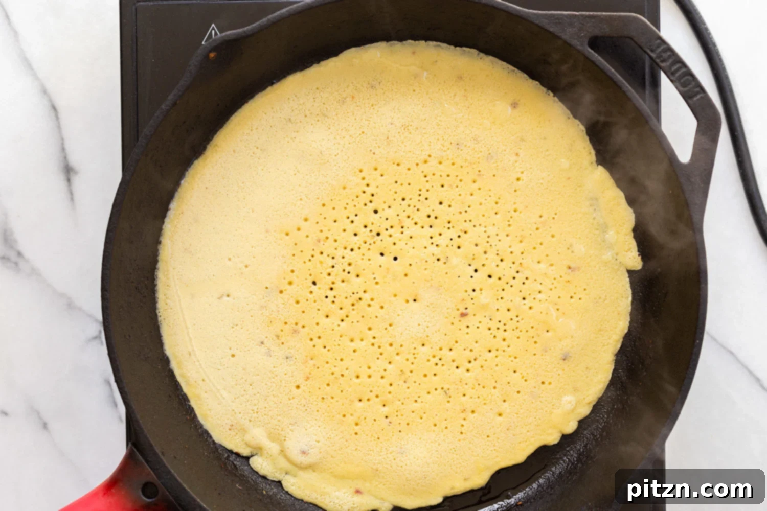 Socca cooking in cast iron skillet