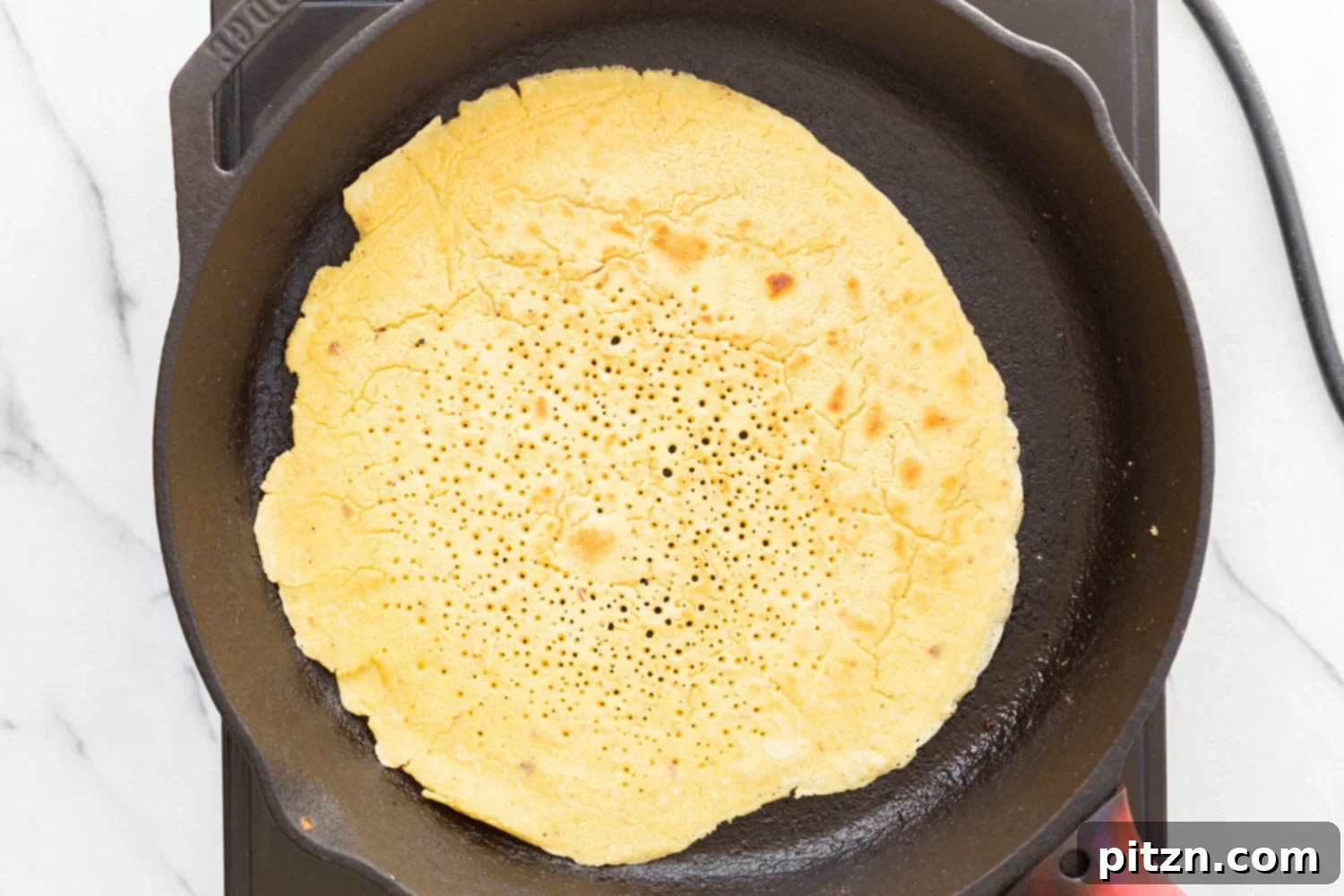 Socca cooking in cast iron skillet