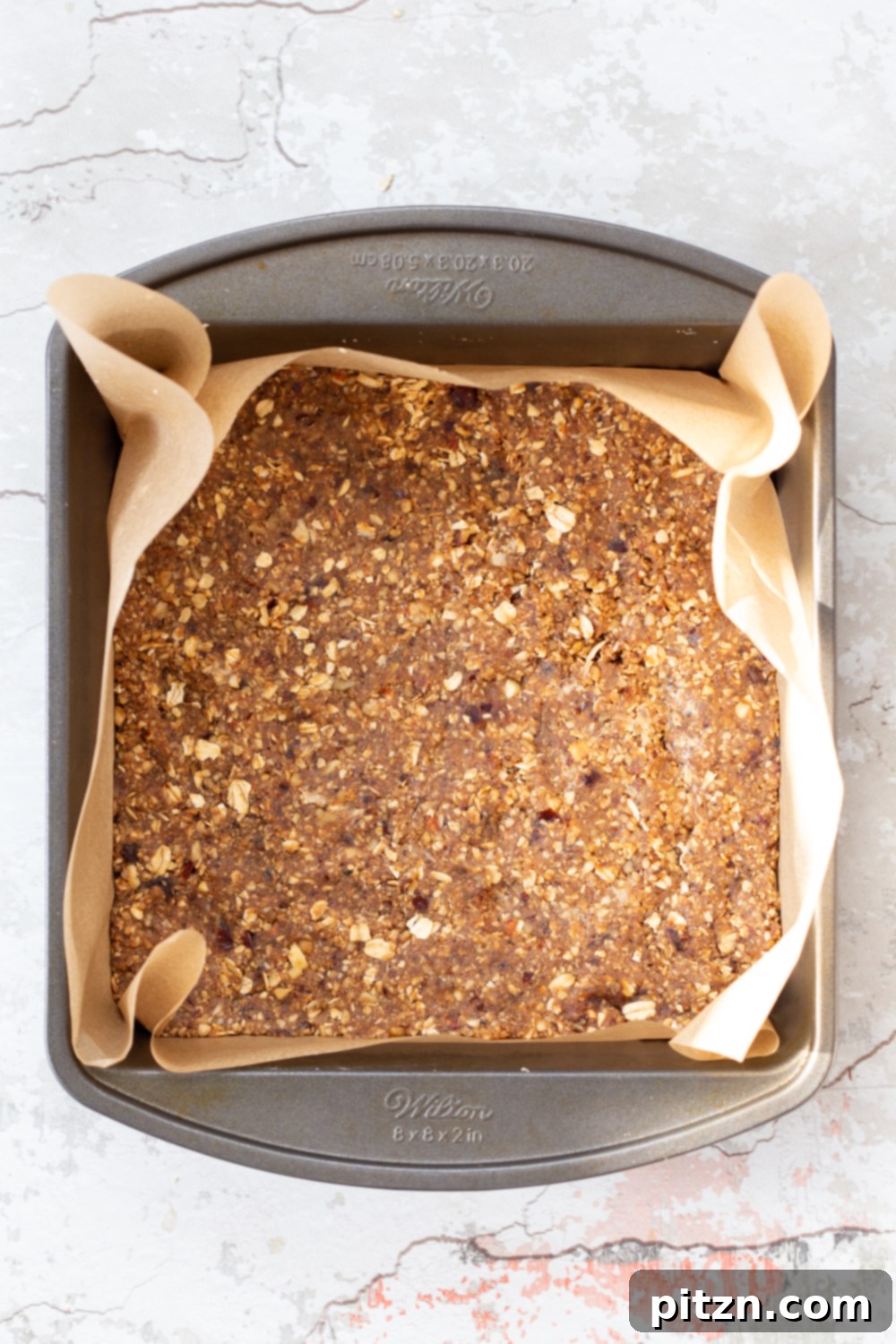 vegan granola bars overhead shot of unbaked vegan banana granola bars in a metal baking pan