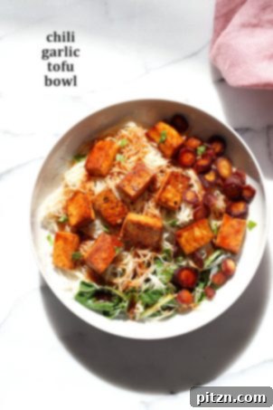 26 Vibrant Vegan Bowl Recipes 4 A close-up of a vibrant vegan bowl featuring roasted vegetables, possibly with a chili-garlic tofu or similar protein, topped with fresh herbs, showcasing a healthy and flavorful meal.