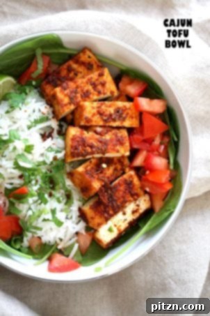 Cajun Tofu with Cilantro Lime Rice. A savory bowl featuring baked Cajun-spiced tofu, fresh greens, fragrant cilantro lime rice, and juicy tomatoes. An easy, spicy, vegan, gluten-free, and nut-free recipe. Soy-free option with chickpea tofu.