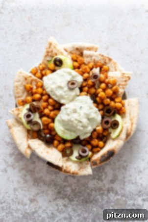 Mediterranean Shawarma Nacho Extravaganza (Vegan) 7 A grand spread of Vegan Mediterranean Nachos with Shawarma Chickpeas, Tzatziki, Olives, and Cucumber on warm toasted pita bread, ideal for any party or potluck.