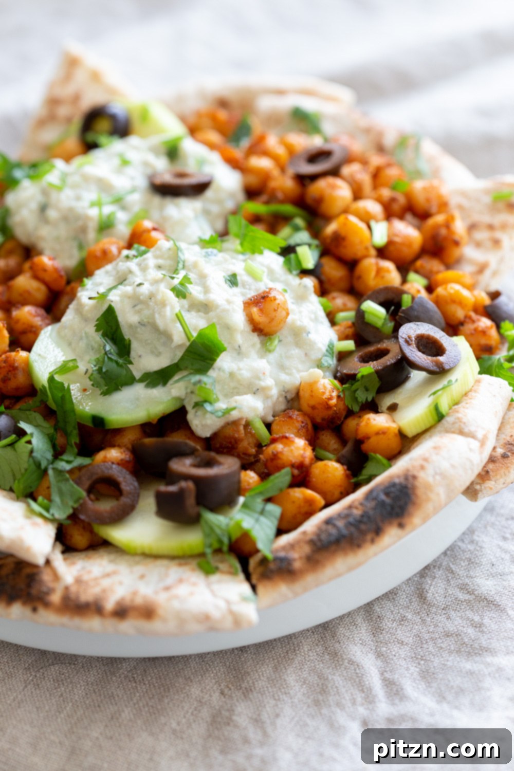 Mediterranean Shawarma Nacho Extravaganza (Vegan) 8 Beautifully plated Vegan Mediterranean Nachos in a white dish, ready to be enjoyed as a party appetizer or healthy meal.