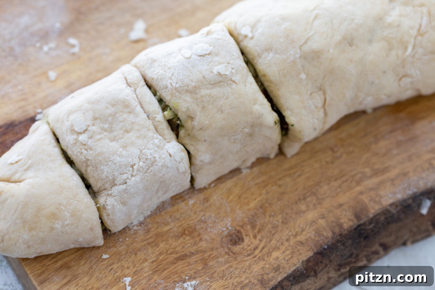 Slicing Pizza Rolls Sliced Pesto Pizza rolls neatly arranged on a cutting board, showcasing their spiral layers of dough, pesto, and mushrooms, ready for baking.