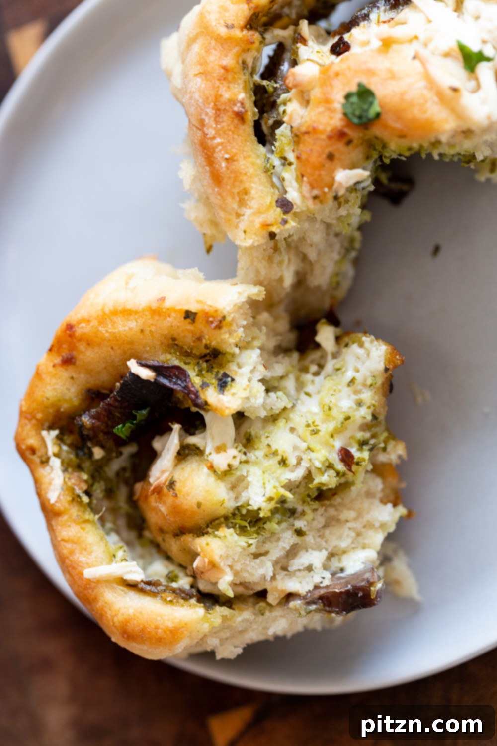 Pesto Pizza Roll Cross-Section A fluffy and soft homemade Vegan Pesto Pizza roll being gently torn into two pieces, revealing the vibrant green pesto and mushroom filling inside.