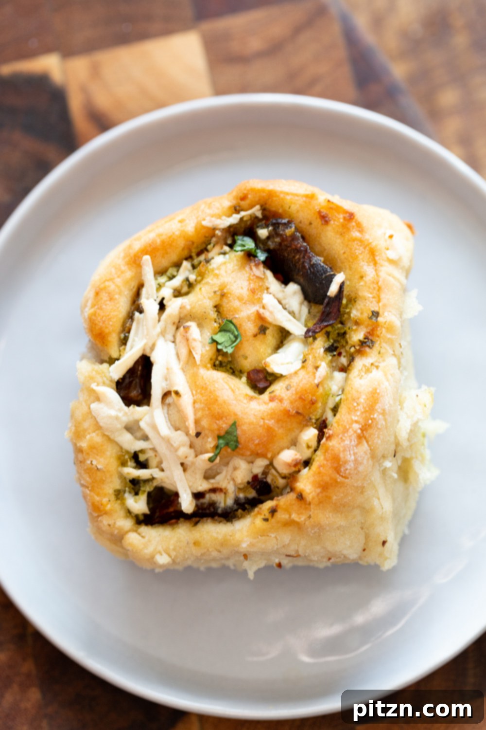 Vegan Pizza Rolls with Cheese Overhead shot of a single vegan Pesto Pizza roll, beautifully topped with melted shredded vegan mozzarella cheese, showcasing its enticing golden crust and vibrant filling.