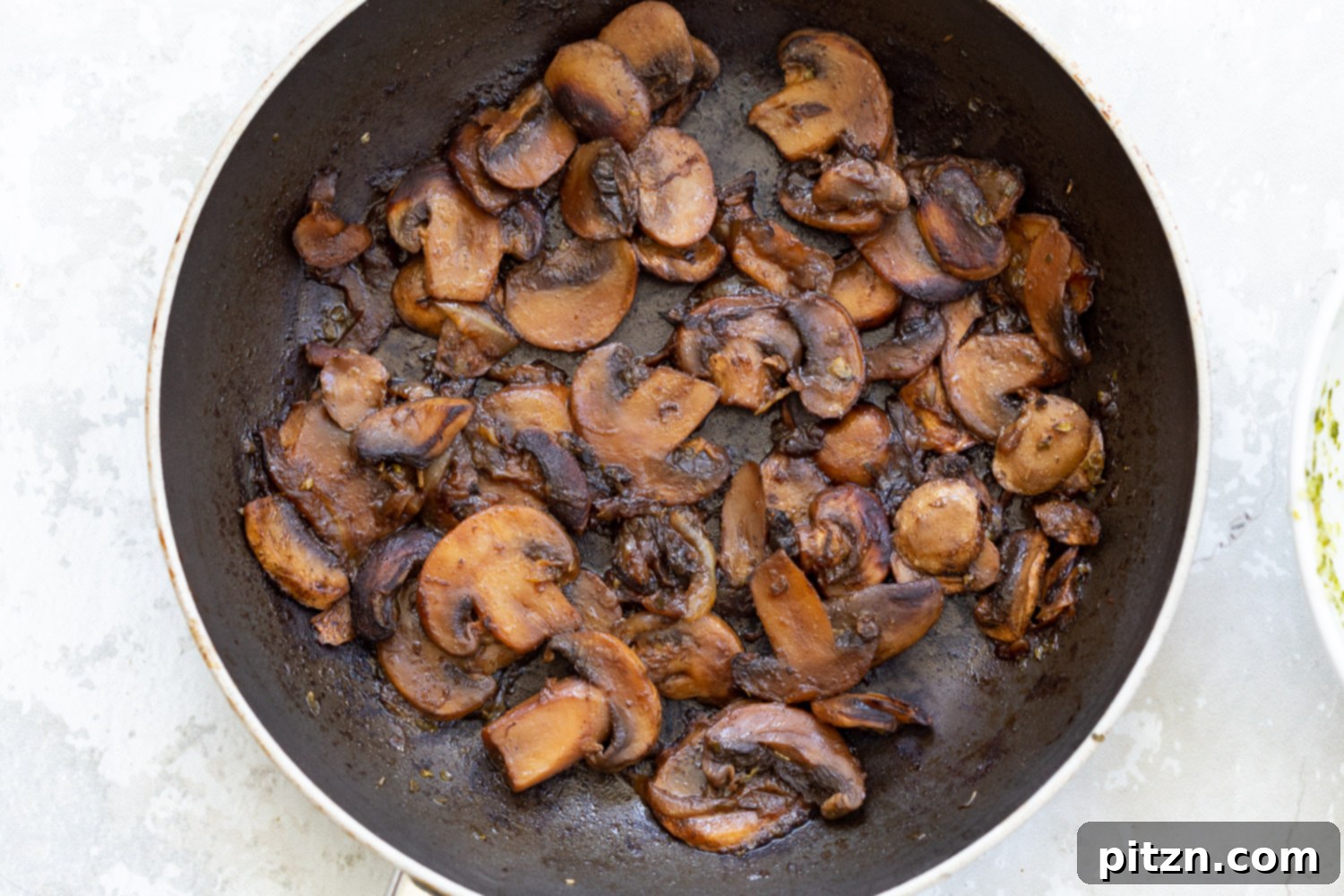 Sautéing Mushrooms for Filling Sliced mushrooms and onions sautéing in a black pan on a stovetop, creating a savory base for the pizza roll filling.