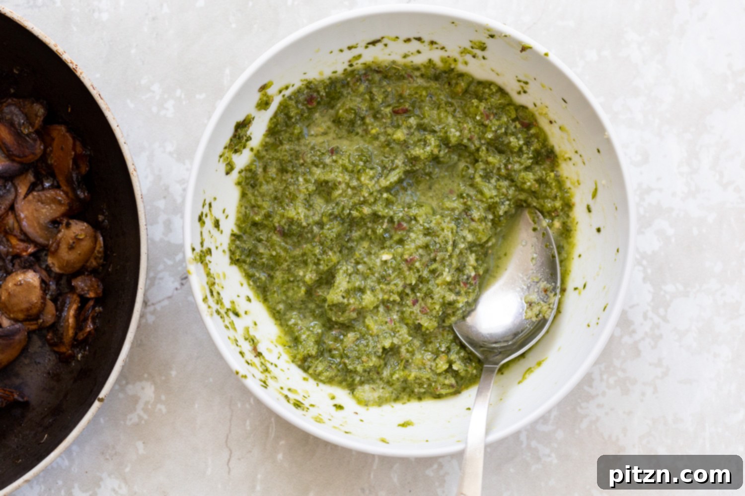 Homemade Vegan Pesto A small white bowl filled with vibrant green homemade vegan pesto, showcasing its fresh, rich texture and inviting aroma.