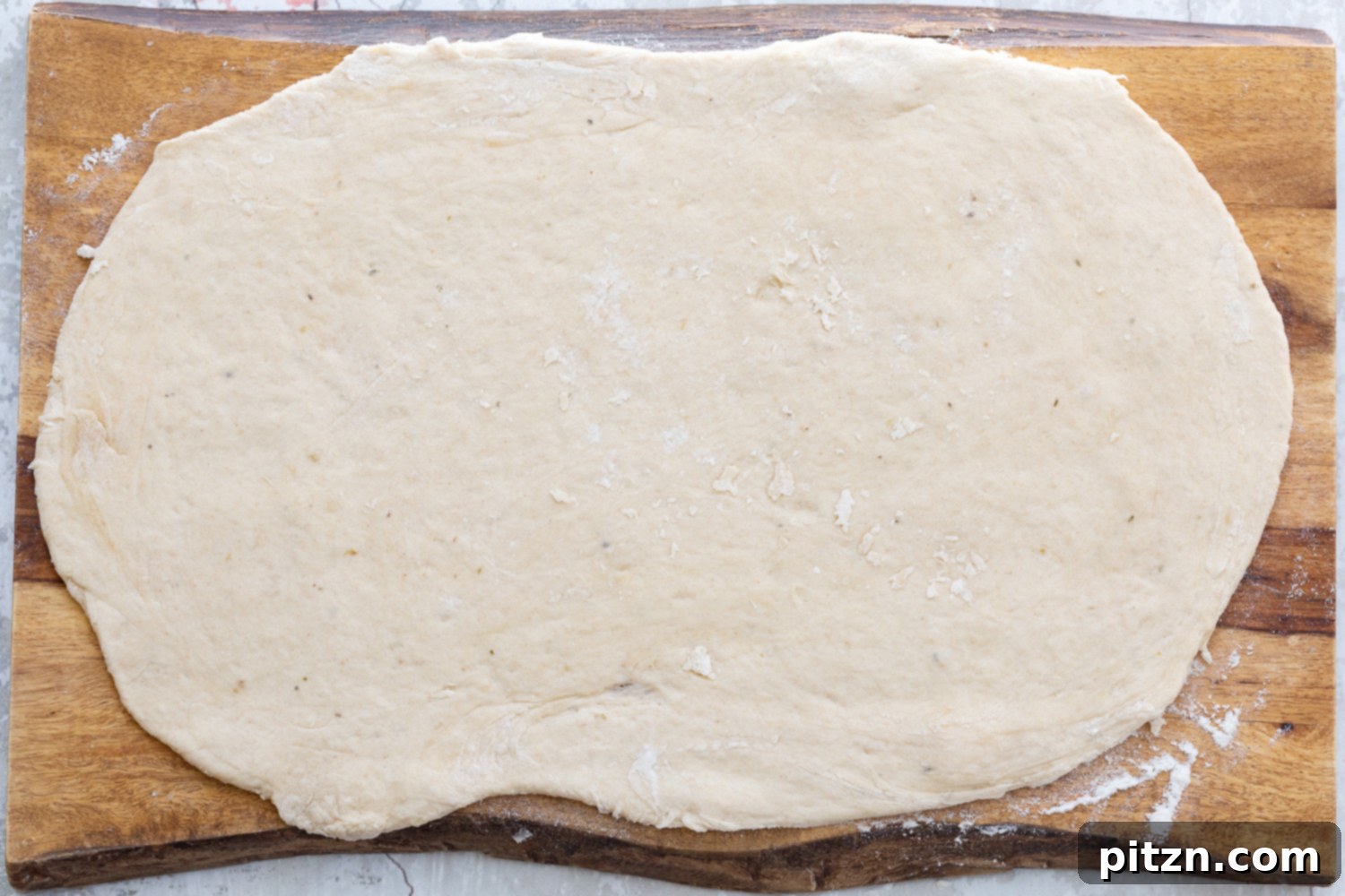 Rolling Out Pizza Dough Vegan pizza roll dough being expertly rolled out into a perfect rectangular shape on a floured surface, ready for the filling.