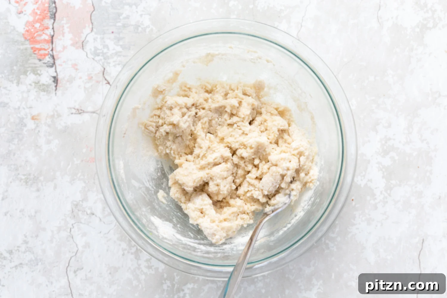Thick, muffin-like dough for the biscuit topping of Vegan Blueberry Cobbler in a glass bowl, prepared and ready to be added to the fruit.