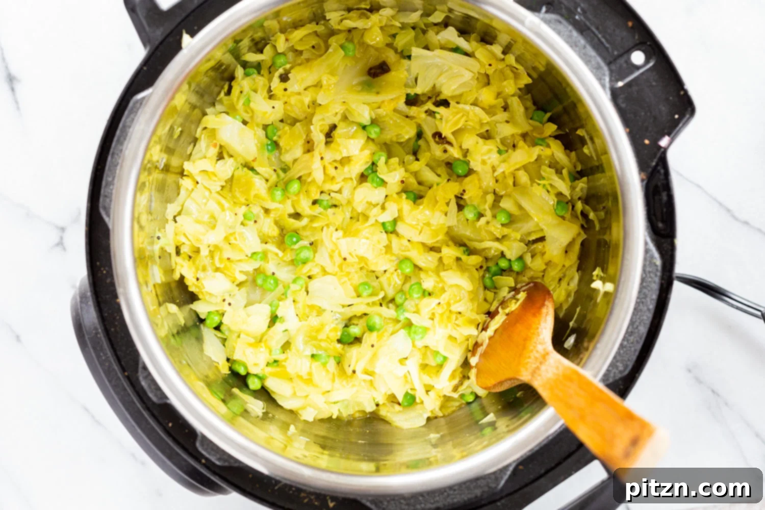 Chopped cabbage mixed with spices inside the Instant Pot, ready for pressure cooking.