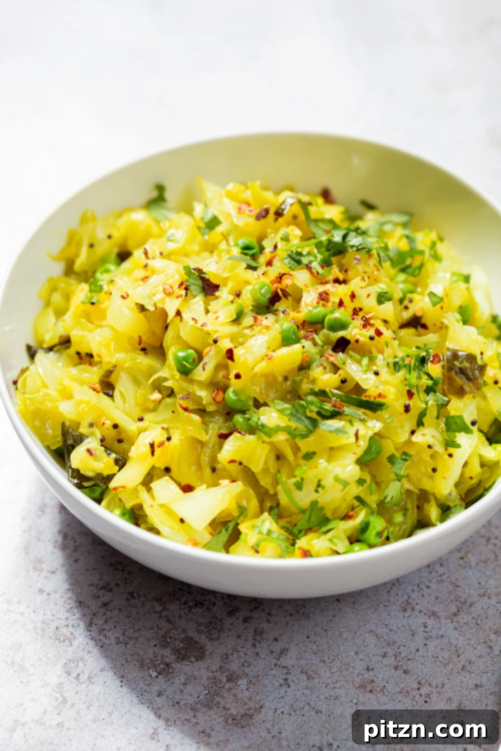 Close-up shot of Instant Pot Indian Cabbage and Peas in a white bowl, garnished with cilantro, ready to eat.
