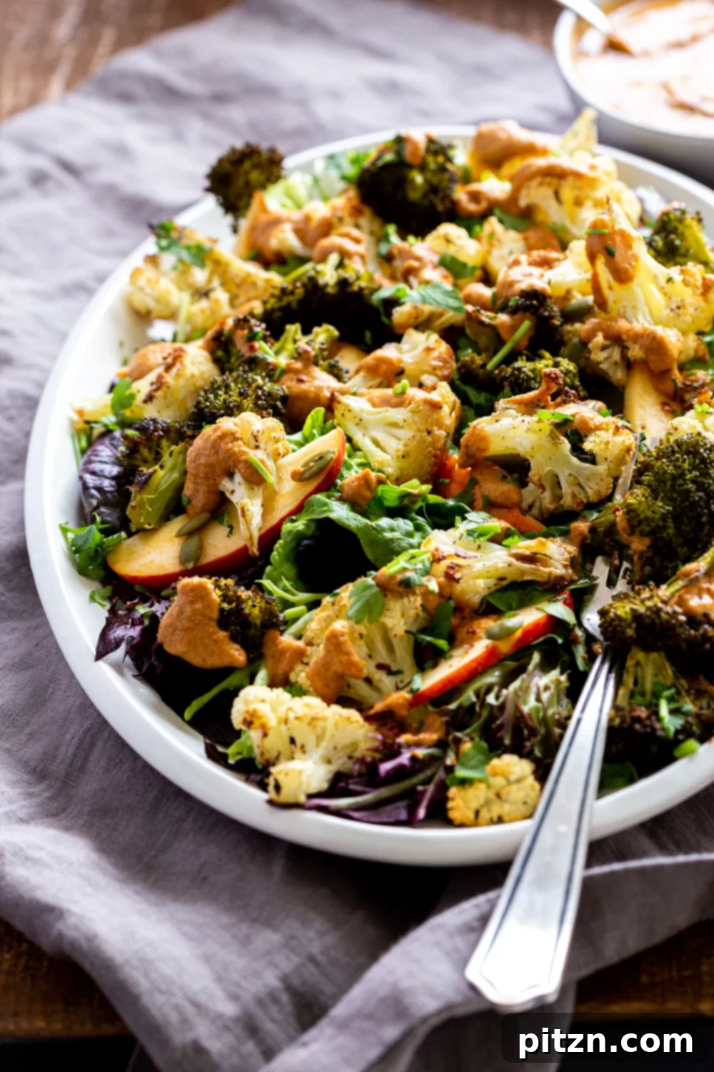 Roasted Broccoli Cauliflower Salad with Sun dried Tomato Dressing on white serving platter, close up
