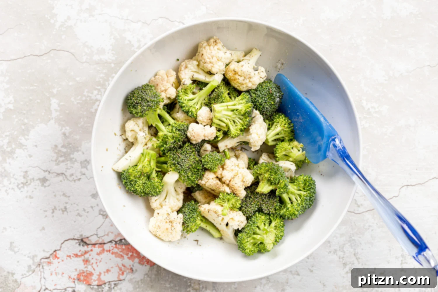 Veggies for our Roasted Broccoli Cauliflower Salad in a white bowl, seasoned