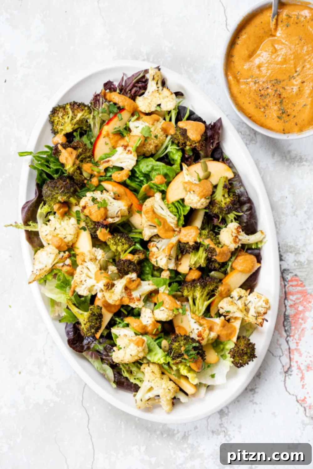 Roasted Broccoli Cauliflower Salad with Sun dried Tomato Dressing on white serving platter, ready to eat