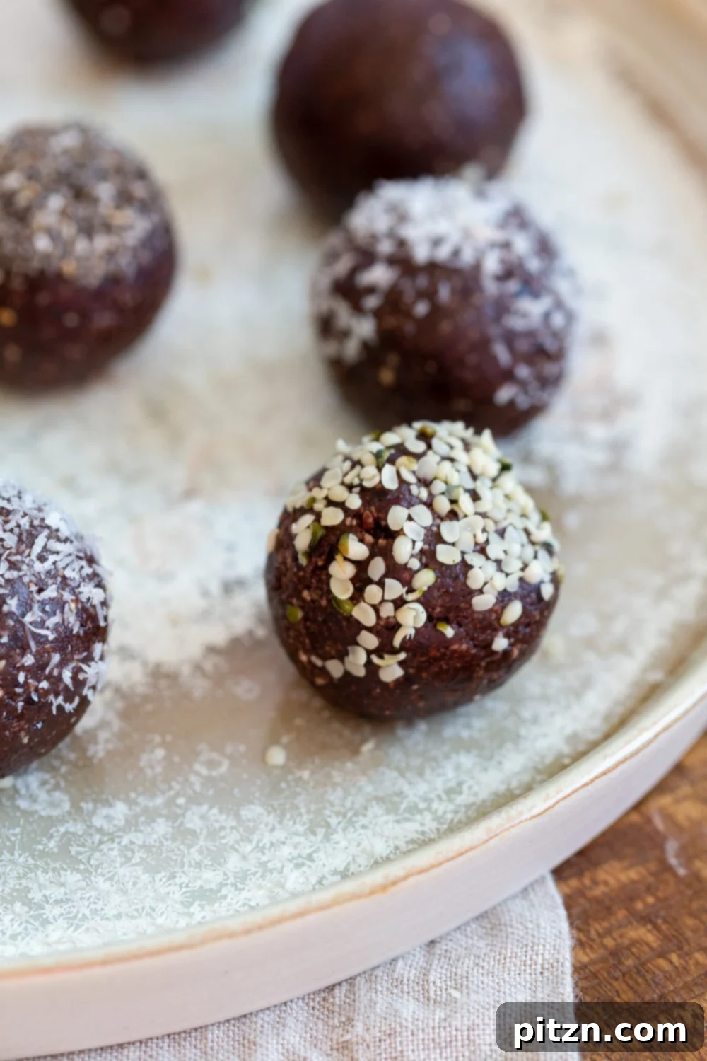 Fudgy Raw Vegan Grain-Free Brownie Bites 2 Delicious Raw Vegan Brownie Bites elegantly arranged on a white speckled plate, showcasing their fudgy texture and dark chocolate hue. Perfect as a quick, healthy, and decadent snack.