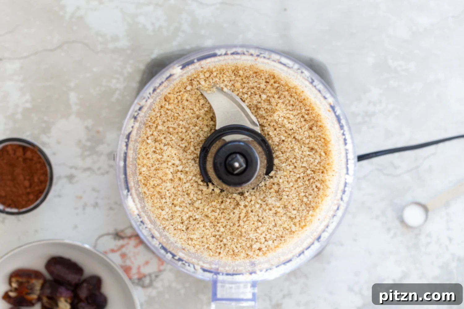 Fudgy Raw Vegan Grain-Free Brownie Bites 6 Cocoa powder added to the processed nuts and coconut in a food processor, ready for blending to create the chocolate base.