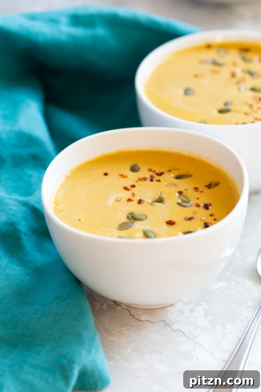 Velvety Vegan Instant Pot Pumpkin Soup 2 Our Creamy Vegan Pumpkin Apple Soup, served beautifully in white bowls, garnished with black pepper and pumpkin seeds