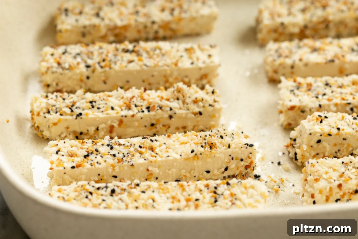 Crispy Everything Bagel Tofu 6 Parchment-lined baking dish filled with breaded Everything Bagel Tofu, ready for the oven