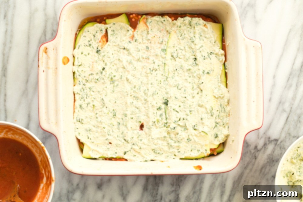 Creamy Vegan Gluten-Free Zucchini Lasagna with Tofu Ricotta 7 Layering the tofu ricotta on Our Vegan Gluten free Zucchini Lasagna in a cream baking dish