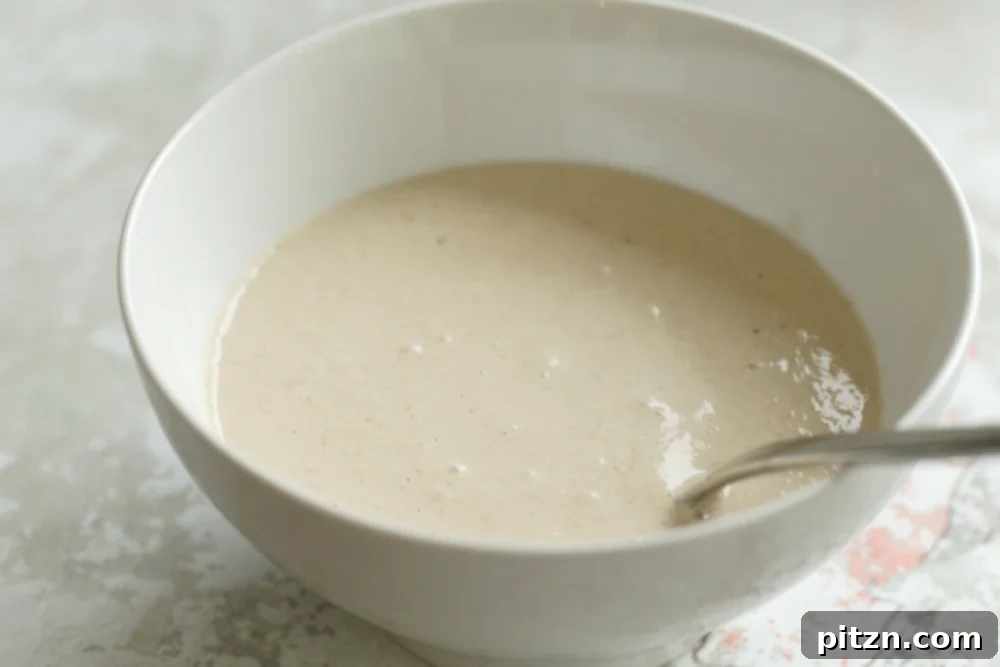 Wholesome Gluten-Free Vegan Banana Oat Pancakes 4 Smooth, creamy batter for Banana Oat Pancakes resting in a white bowl, ready for cooking.