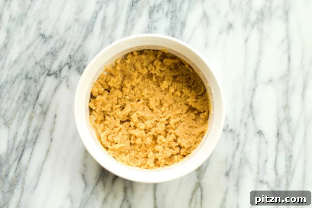 The almond flour carefully mixed into the sugar and water base for our Vegan Almond Halwa, in a white baking dish.