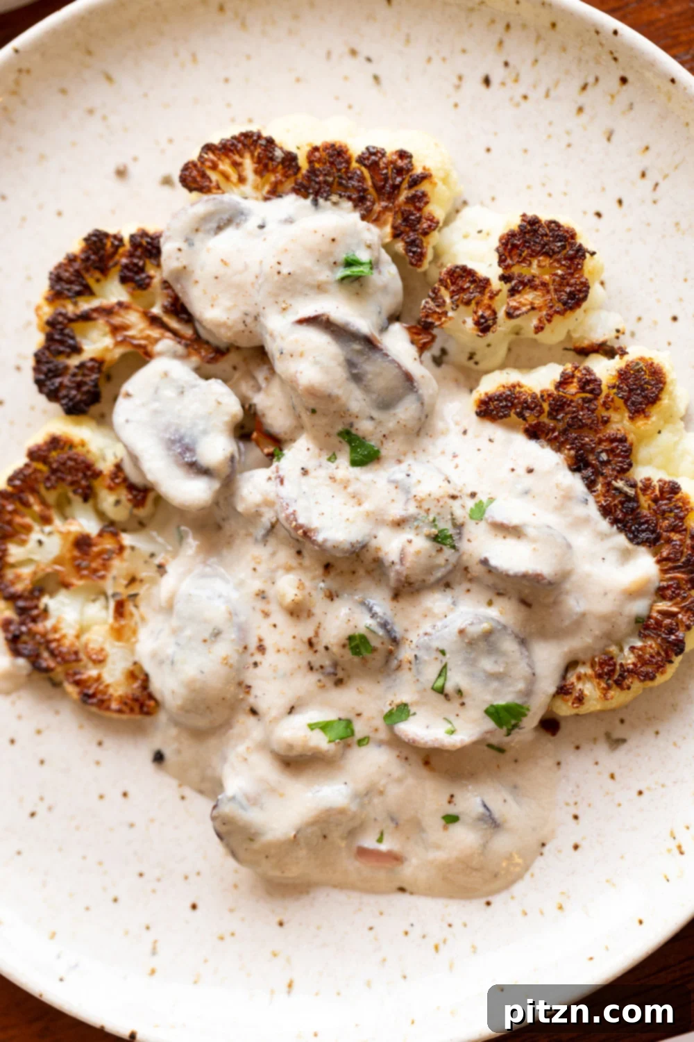 Vegan Mushroom Sauce served with a roasted cauliflower steak on a white plate