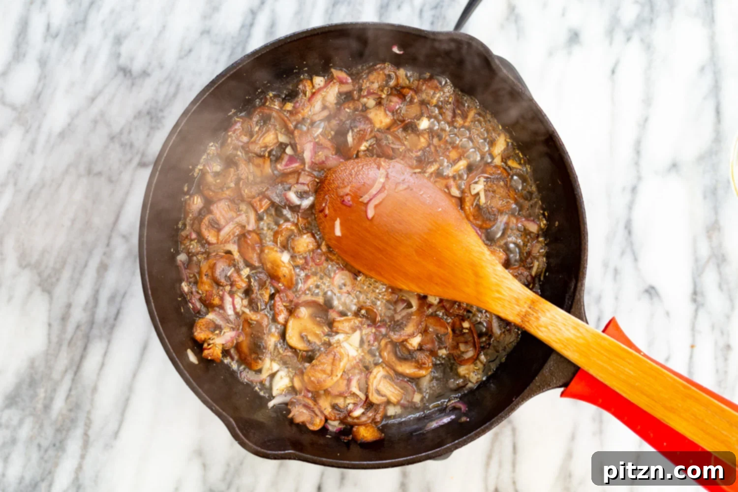Mushrooms and white wine simmering in a cast iron skillet