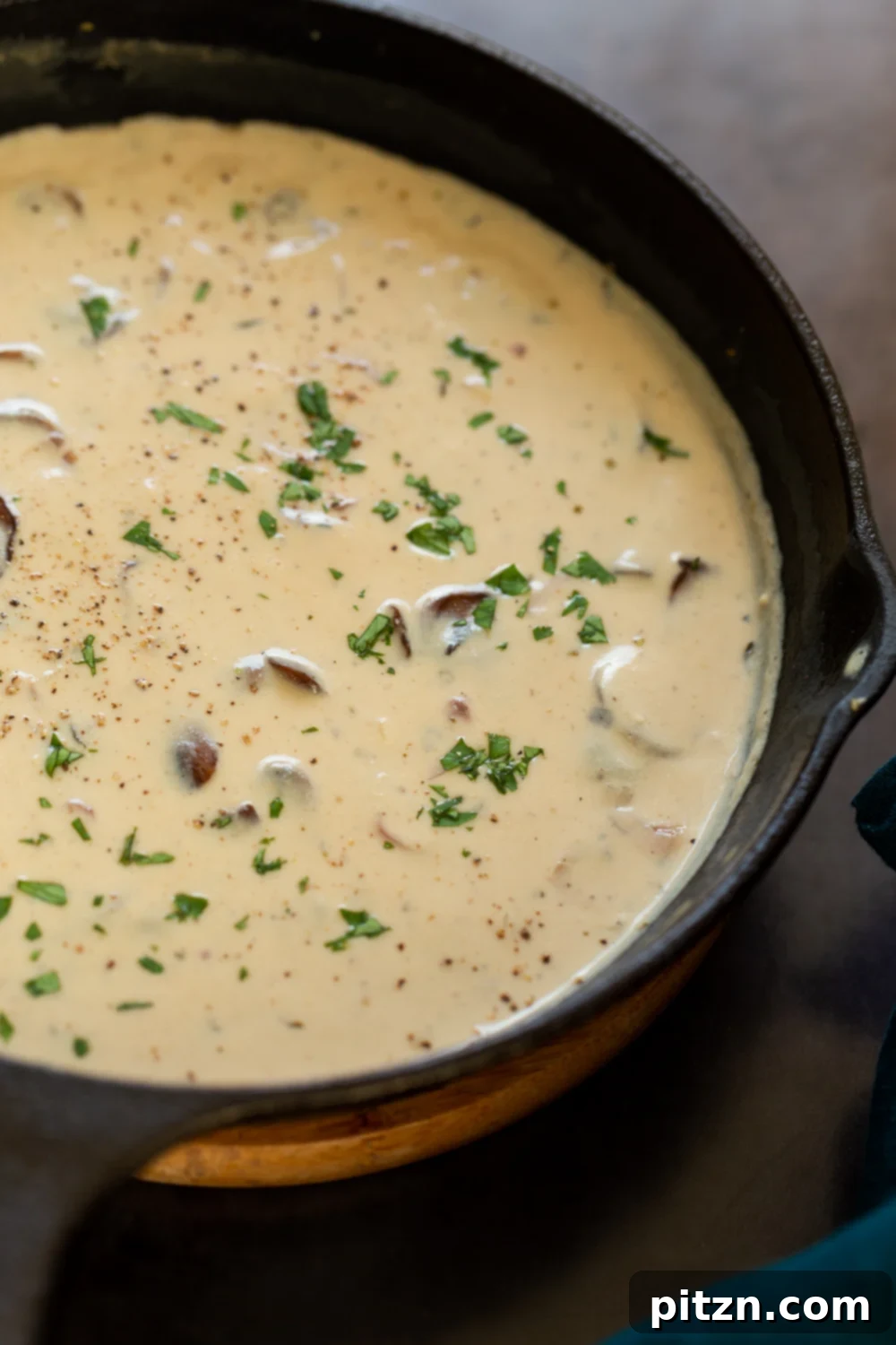 Creamy Vegan Mushroom Sauce in a black skillet with a wooden spoon