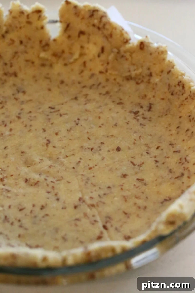 almond flour pie crust side view of a vegan gluten-free almond flour pie crust placed in a glass pie dish ready for baking
