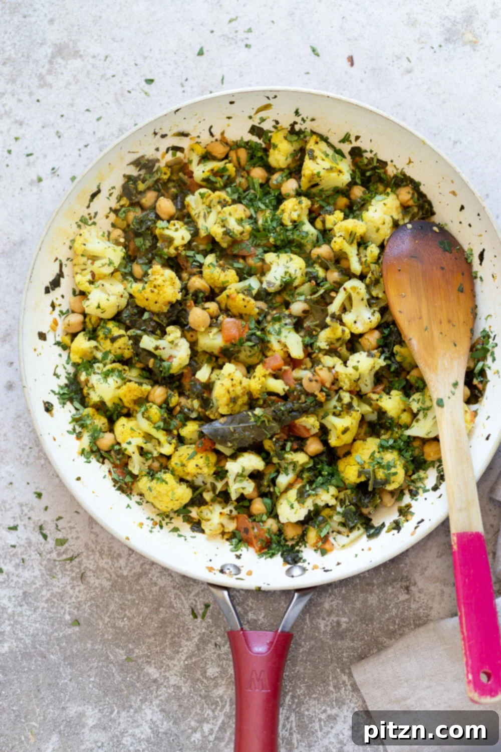 overhead shot of a pan with cauliflower, chickpeas and spinach sauteed with Indian spices