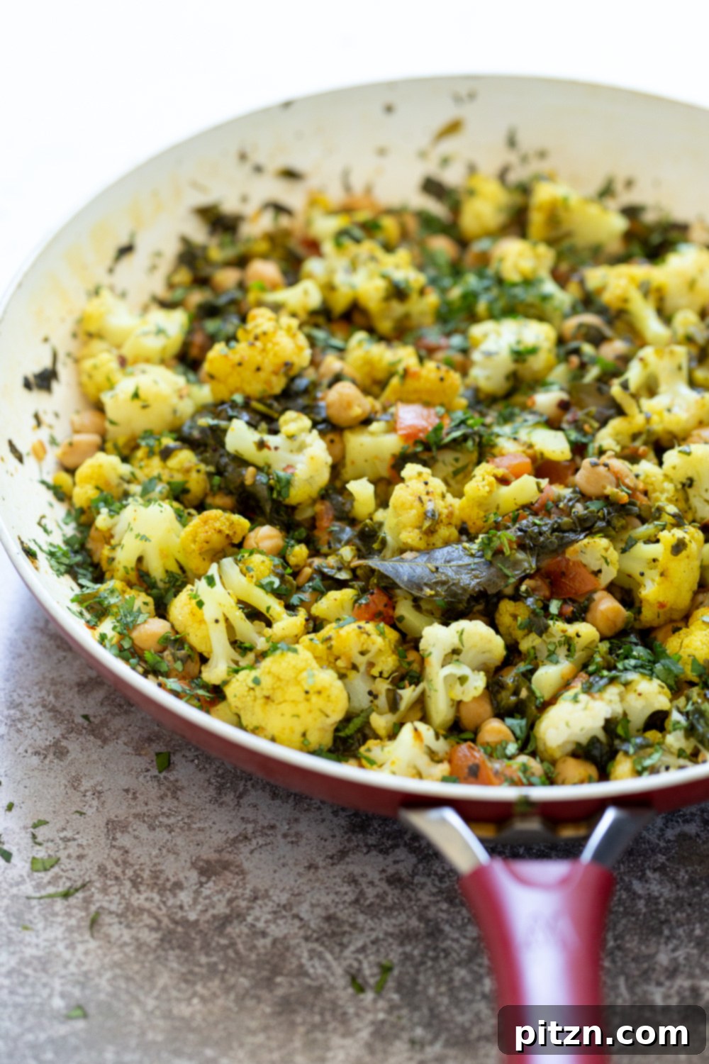 side view of a pan with cauliflower, chickpeas and spinach sauteed with Indian spices 