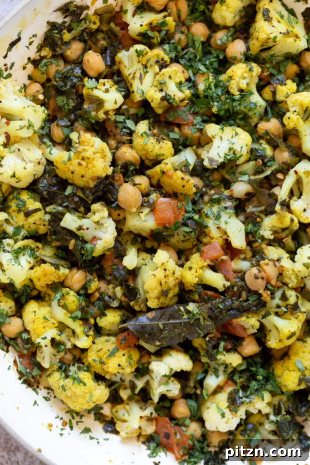 close-up overhead shot of a frying pan with cauliflower, chickpeas and spinach saute
