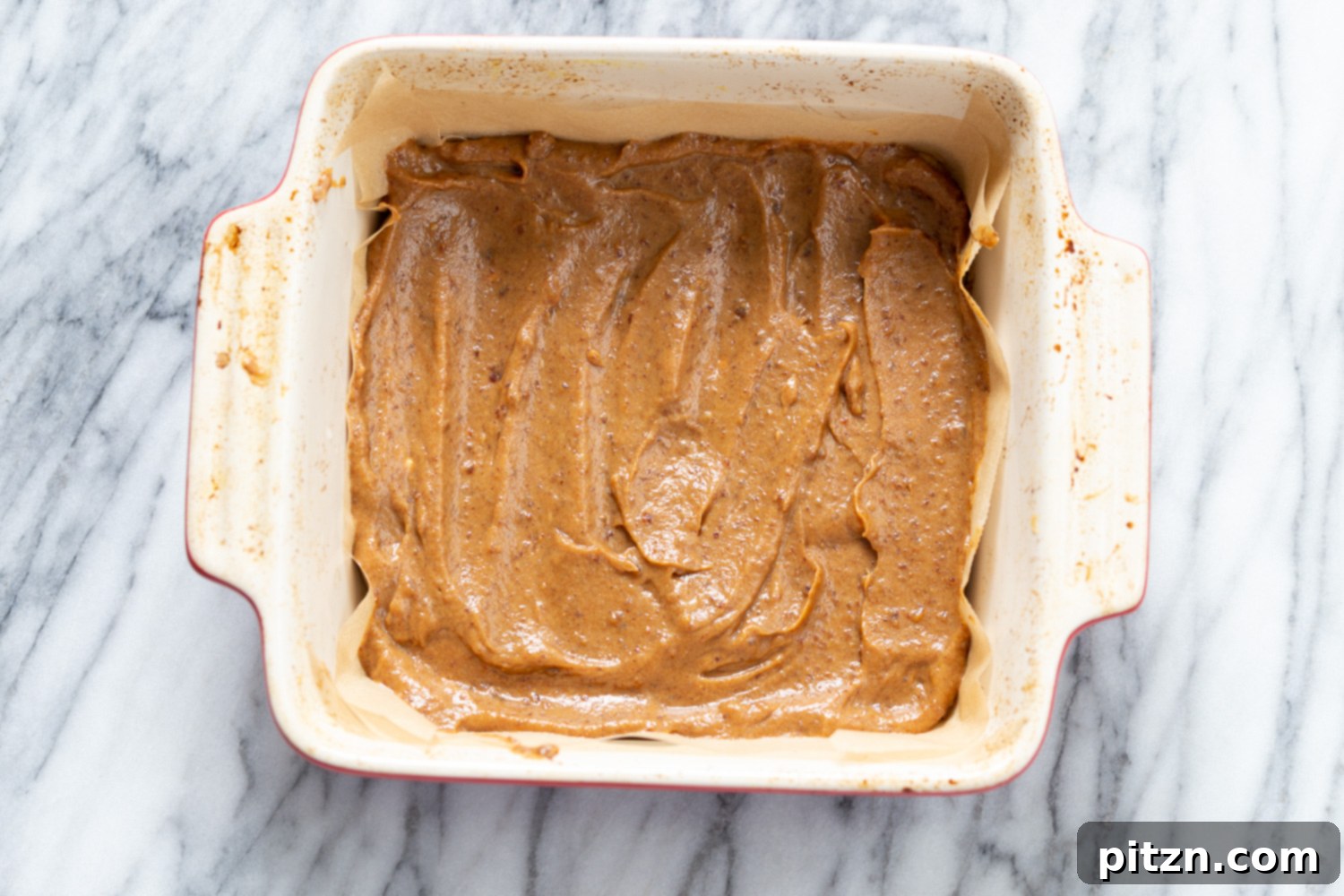 snickers recipe homemade vegan date caramel being spring onto cookie base to make vegan snickers snack bars recipe
